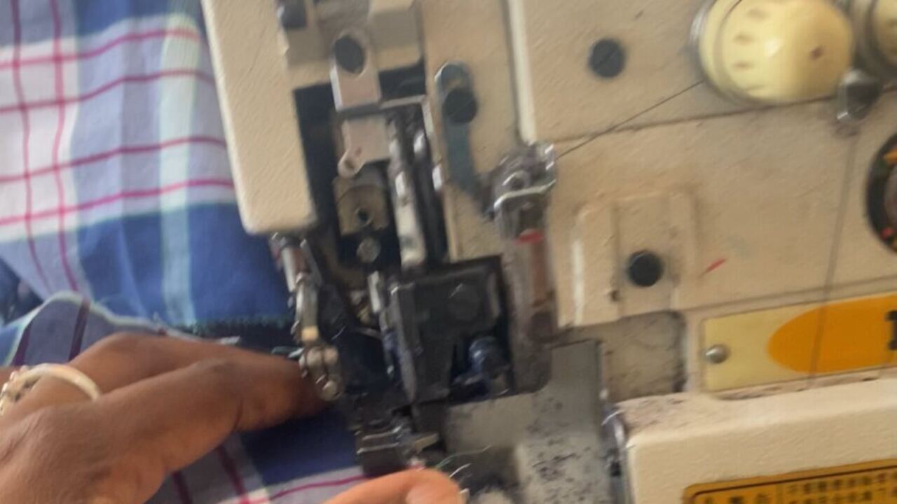 Hands guiding fabric through an industrial sewing machine